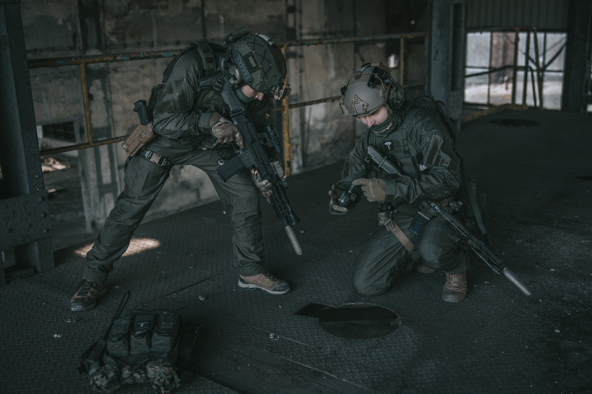 Two soldiers in tactical gear in a dimly lit industrial setting
