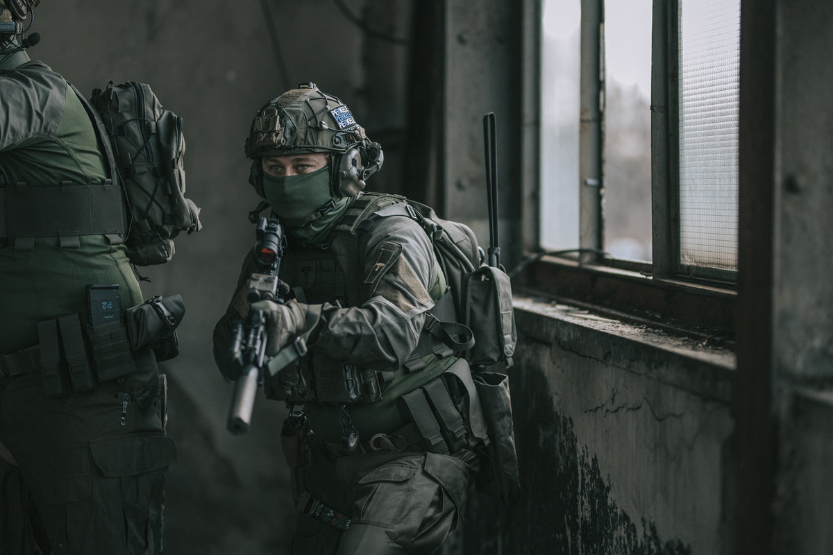 Person in tactical gear with a rifle in an indoor setting