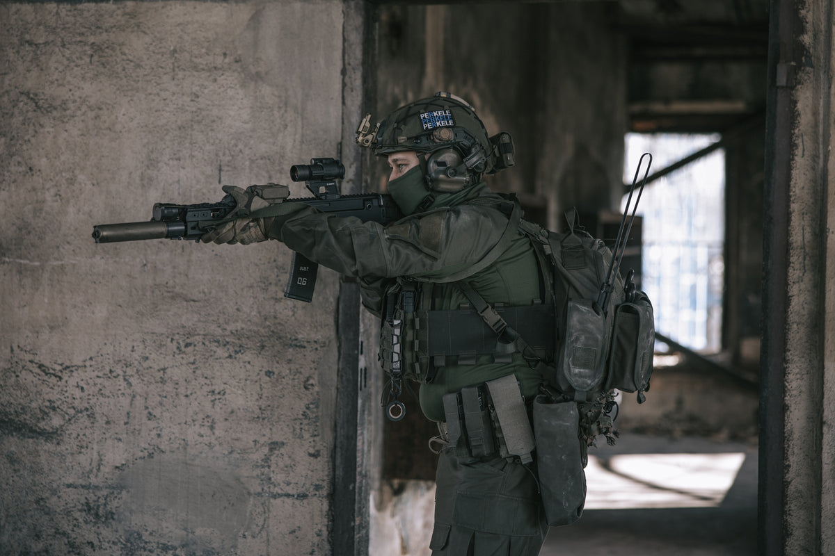 Person in tactical gear holding a rifle in an urban setting