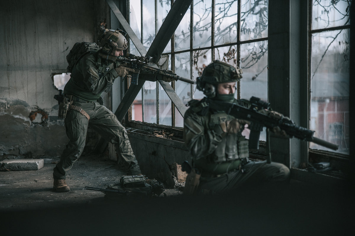 Two soldiers in tactical gear in a dimly lit industrial setting