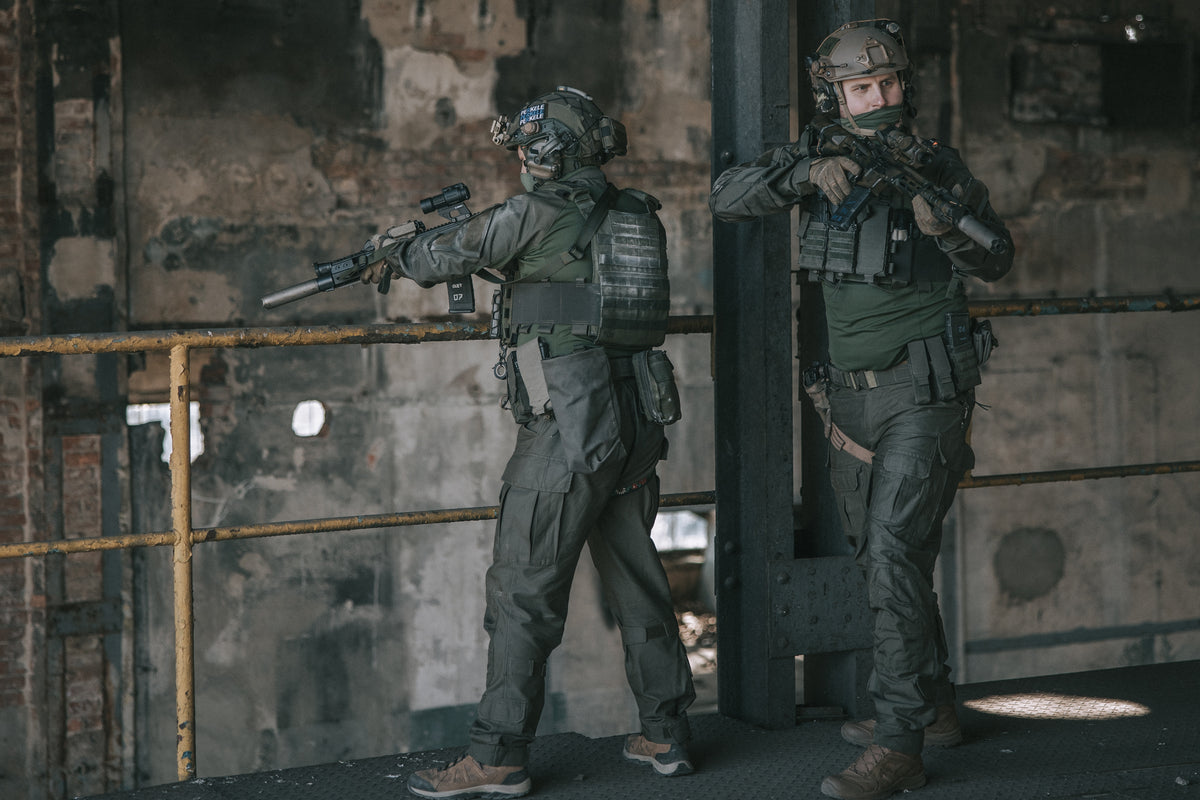 Two soldiers in tactical gear in a dimly lit industrial setting
