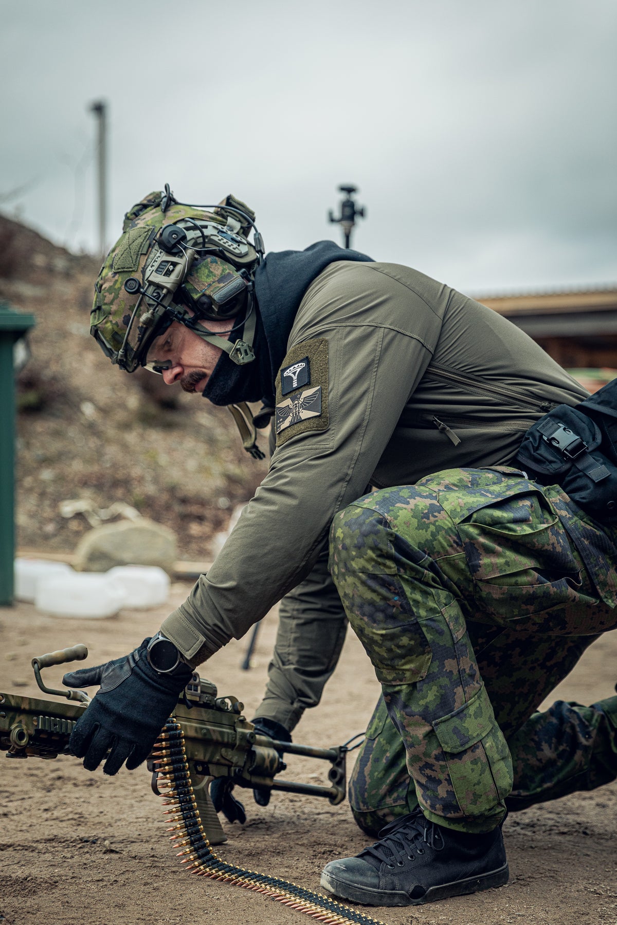 Person in military gear with a rifle  kneeling down and reloading the rigle.