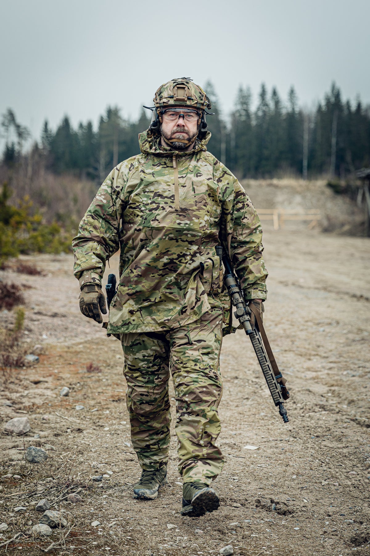 Person in camouflage gear holding a rifle at a shooting range.