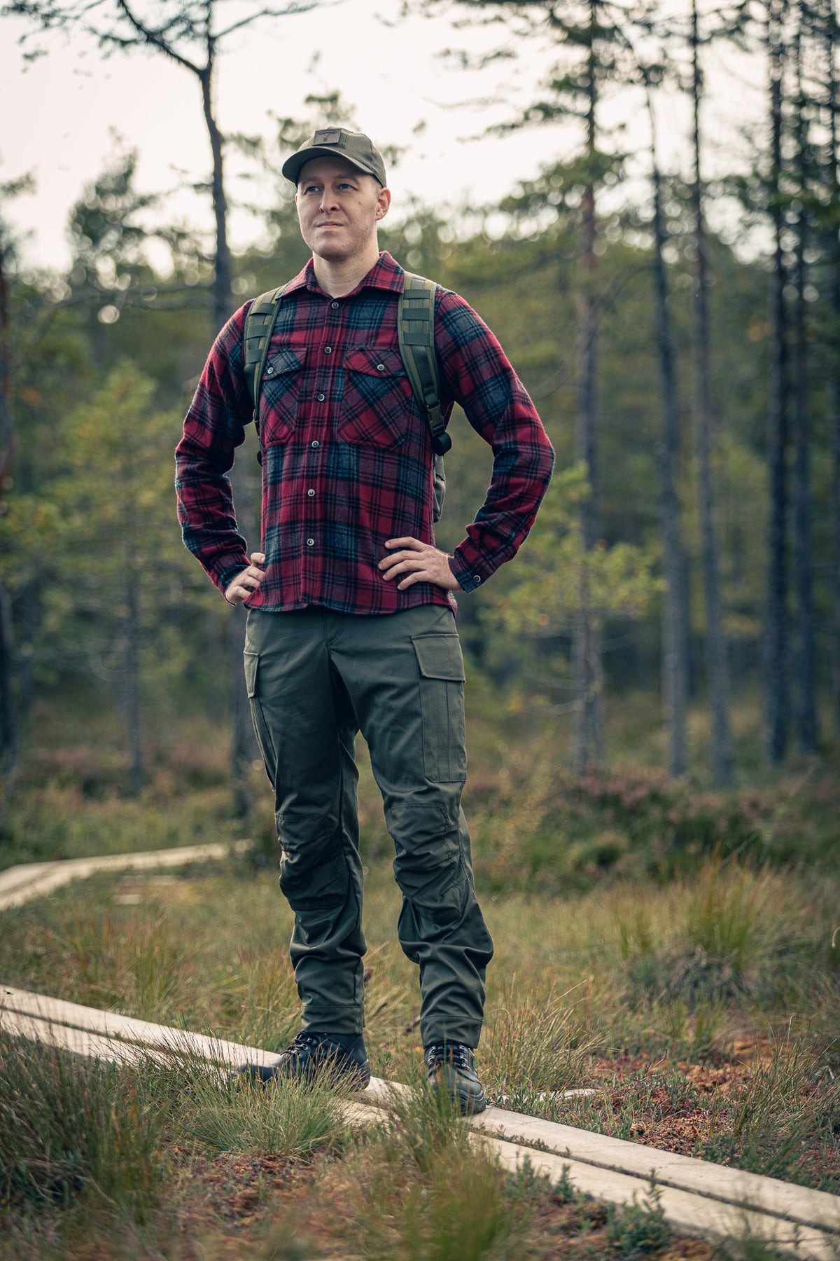 Man in outdoor attire with a backpack standing in a forest