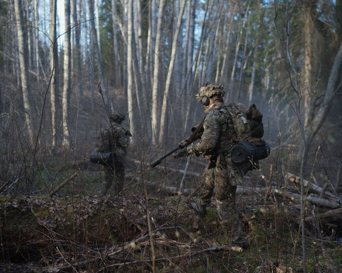 A soldier in a birch forest wearing a helmet with MultiCam Savotta Helmet Camo Scrim.